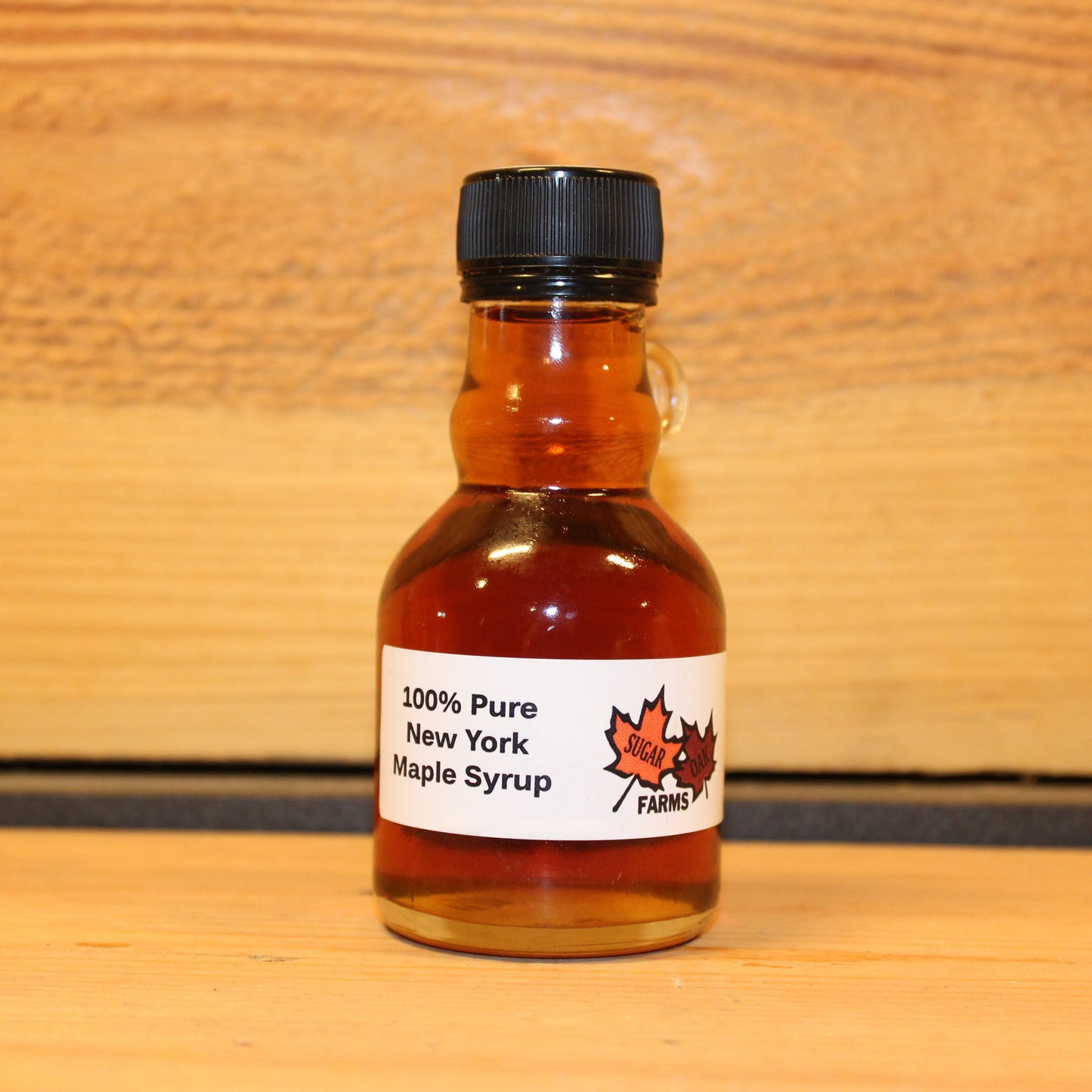 8 fl. oz. glass bottle of amber maple syrup on a wooden surface.